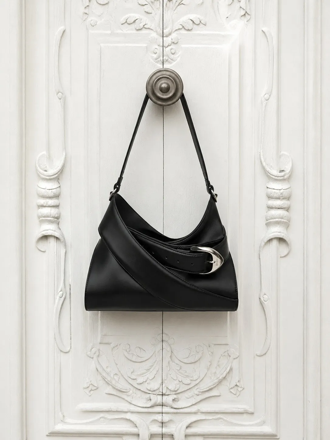 Bolso de piel colgado en una puerta antigua